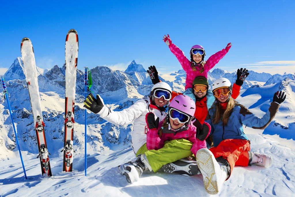 Happy family enjoying winter vacations in mountains . Ski, Sun, Snow and fun.