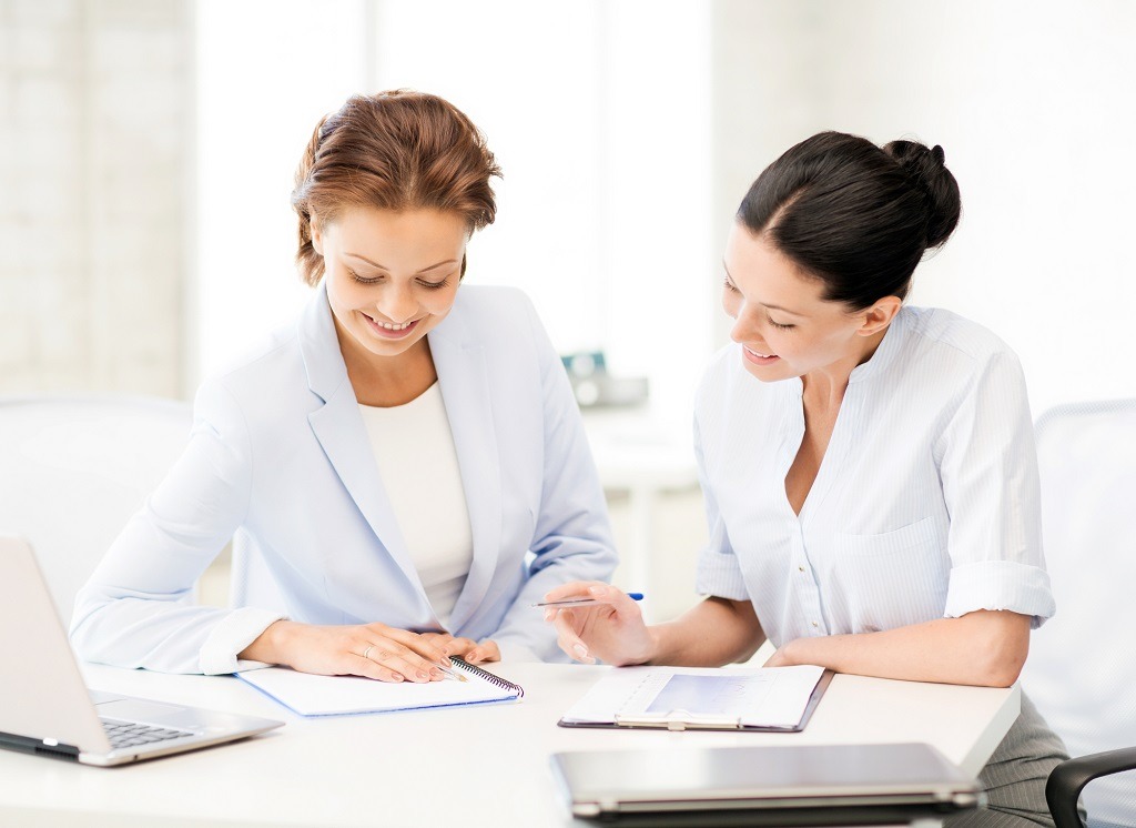 two smiling businesswomen working in office